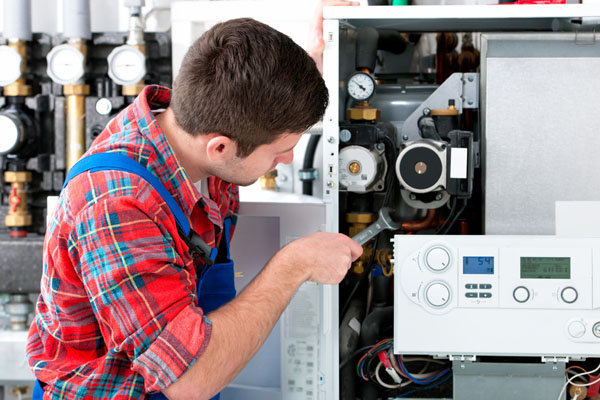 Heating technician repairing boiler controls in Reedley