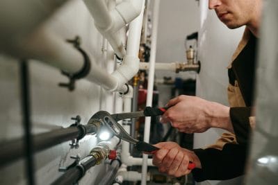 Technician inspecting commercial plumbing pipes in Reedley