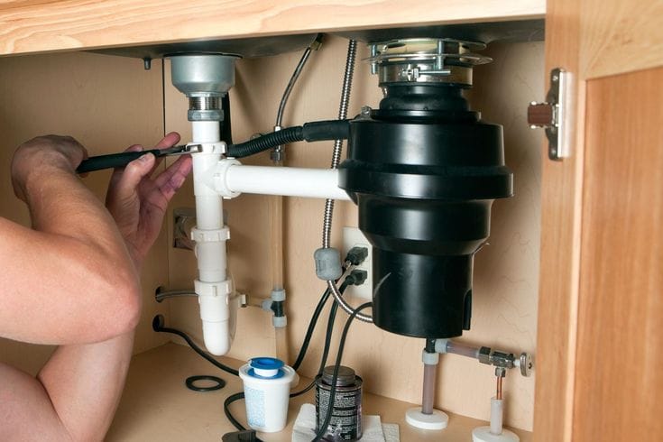 Plumber repairing a garbage disposal in Reedley