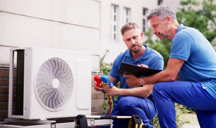 HVAC technicians installing an outdoor air conditioning unit in Reedley
