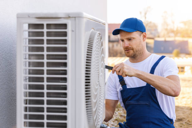 HVAC technician servicing an outdoor air conditioner in Reedley