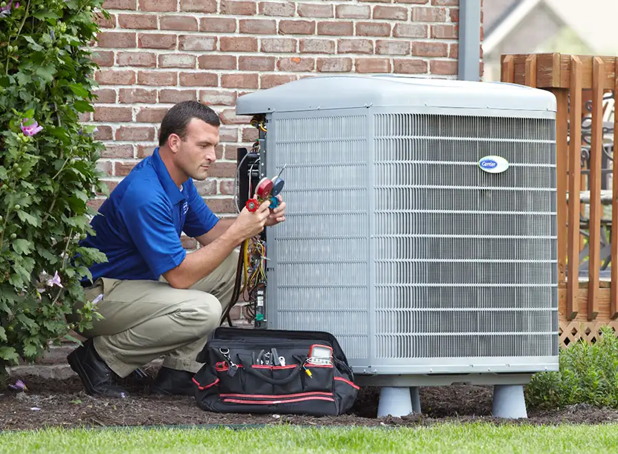 HVAC technician inspecting an outdoor AC unit in Reedley